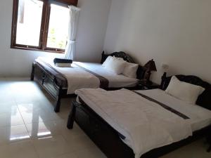 a bedroom with two beds and a window at Double One Villas Amed II in Amed