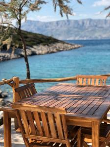 a wooden table and chairs sitting next to the water at Holiday House Trovna in Pučišća