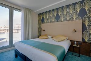a hotel room with a bed and a large window at Best Western Hôtel Journel Antibes Juan-les-Pins in Antibes