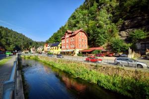 einen Fluss mit Autos, die an einer Straße geparkt sind in der Unterkunft Pension-Restaurace Lugano in Hřensko