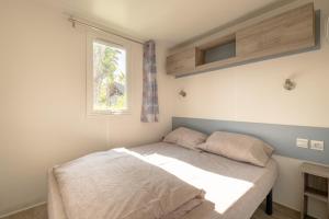 Bett in einem Zimmer mit Fenster in der Unterkunft Marino Mobilhomes in Grimaud