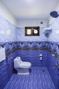 a blue bathroom with a toilet and a window at LEISURE VALLEY BEACH RESORT in Varkala