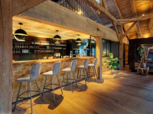 a bar with stools in a kitchen with wooden ceilings at Chalet 1703 - Alpine Lodge & Spa - Adults Only in Le Petit-Bornand-lès-Glières