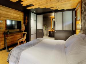 a bedroom with a large white bed and a television at Chalet 1703 - Alpine Lodge & Spa - Adults Only in Le Petit-Bornand-lès-Glières