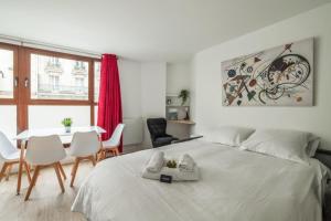 een slaapkamer met een wit bed en een tafel en stoelen bij Bright and cosy flat at the heart of Paris in a trendy district - Welkeys in Parijs