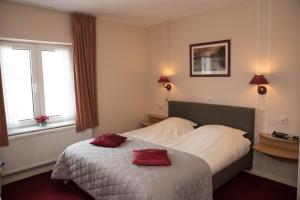 a bedroom with a bed with two red pillows on it at B&B Vouwere in Mechelen