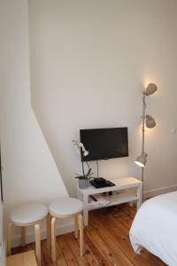 une chambre avec un lit, une télévision et deux tabourets dans l'établissement La Terrasse de Wilson, à Toulouse