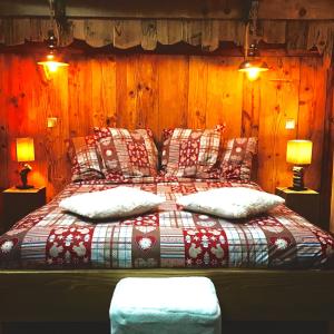 a bed in a room with wooden walls at Ferme familiale chez Lili in Alex