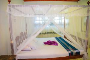 una camera da letto con un letto a baldacchino di VILLA No34 HIKKADUWA a Hikkaduwa Altre 32 foto