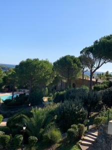 een tuin met bomen en struiken en een zwembad bij SAINT RAPHAEL, CAP ESTEREL Le Hameau. Vue mer in Saint-Raphaël