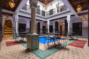 a room with a pool and tables and chairs at Riad Medina Art & Suites in Marrakesh