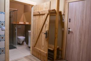 a bathroom with a wooden door and a toilet at Domek Górski przy Bukowej Chacie in Jugów
