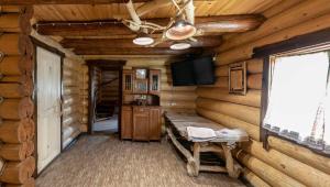 a living room in a log cabin with a television at Gostynna sadyba Kit Bayun in Teterivka