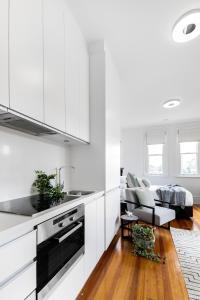 a kitchen with white cabinets and a living room at Designer Styled Studio in Central Trendy Glebe DUPLICATE in Sydney