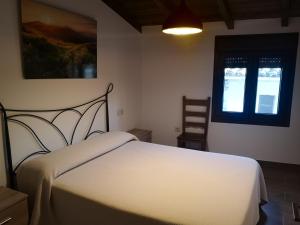 Un dormitorio con una cama blanca y una ventana. en Apartamento Rural La Brígida, Rubiaco, LAS HURDES nº TR-CC-295, en El Rubiaco