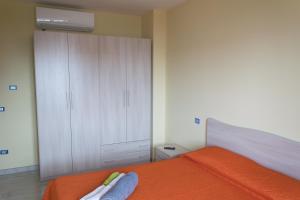 1 dormitorio con cama naranja y armario blanco en Stella d'Oro en Vibo Valentia