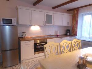 una cocina con armarios blancos y una mesa con sillas. en Im Haus am Ries en Ehingen am Ries