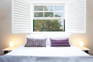 uma cama com duas almofadas num quarto com uma janela em Woolwich Studio Bliss, Private Oasis by the Water em Sydney