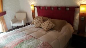 Stellamar Apart Hotel في لا سيرينا: غرفة نوم بسرير مع وسادتين وكرسي