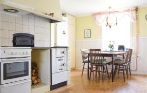 a kitchen with a stove and a table with chairs at Nice Home In Ankarsrum With House A Panoramic View in Ankarsrum