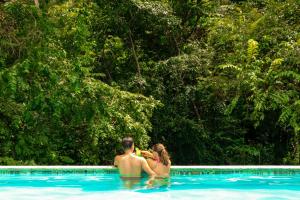 un hombre y una mujer sentados en una piscina en Teva Hotel & Jungle Reserve en Manuel Antonio