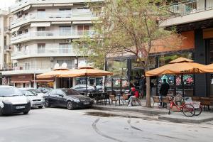a person sitting at a table under umbrellas on a city street at Casa Georgina in Thessaloniki