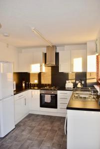 uma cozinha com armários brancos e bancadas pretas em Kelpies Serviced Apartments Hamilton- 2 Bedrooms em Falkirk