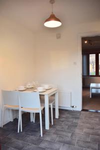 Kelpies Serviced Apartments Hamilton- 2 Bedrooms في فالكيرك: غرفة طعام مع طاولة بيضاء وكراسي