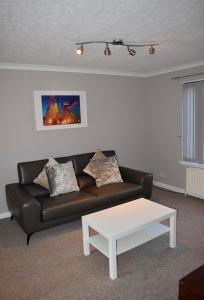 sala de estar con sofá negro y mesa de centro blanca en Kelpies Serviced Apartments Hamilton- 2 Bedrooms en Falkirk