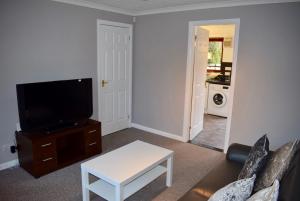 a living room with a couch and a tv at Kelpies Serviced Apartments Hamilton- 2 Bedrooms in Falkirk