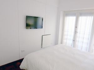 een witte slaapkamer met een bed en een tv aan de muur bij Cabo Corrientes Center in Mar del Plata
