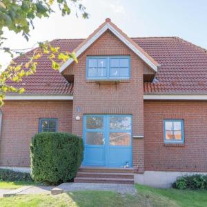 une maison en briques rouges avec une porte bleue dans l'établissement Ferienwohnung-Stinson-Beach, à Lemkenhafen auf Fehmarn