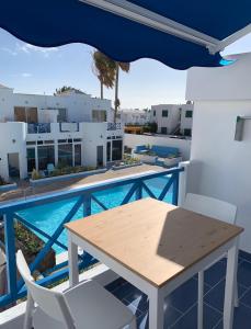 a table and chairs on a balcony with a swimming pool at Puerto del Carmen Luxury Apartment in Tías