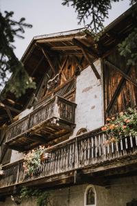 a building with wooden balconies and flowers on it at Bäcksteinerhof in Merano