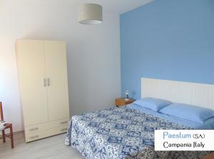 ein blaues Schlafzimmer mit einem Bett und einem Schrank in der Unterkunft Goethe Paestum House in Paestum