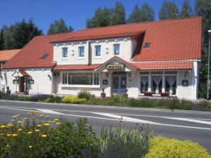 a white building with an orange roof on the side of a road at Hotel Mühleneck in Hage