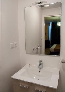 een badkamer met een witte wastafel en een spiegel bij Hôtel des Pyrénées in Angoulême