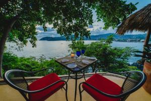 a table and chairs with a view of the water at Espuma Hotel - Adults Only in Zihuatanejo +27 photos