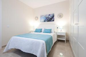 una camera bianca con un grande letto con cuscini blu di El faro a Las Playitas