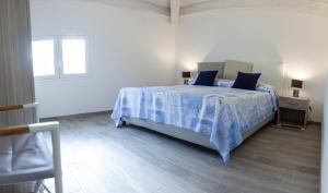 1 dormitorio con cama con sábanas azules y ventana en L'Ancora Holidays, en Punta Secca