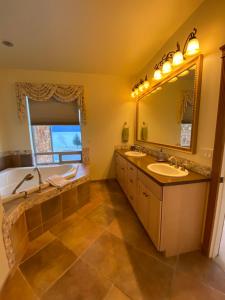 a bathroom with two sinks and a tub and a mirror at Seward Front Row Townhouse in Seward