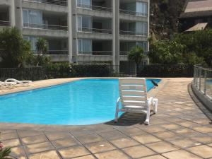 a chair sitting next to a swimming pool with a building at Playa Miramar in Viña del Mar