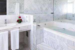 
a white bath tub sitting next to a white sink at Hotel Suites Albayzin Del Mar in Almuñécar
