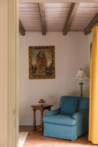 a living room with a blue chair and a picture on the wall at Monasterio, A Belmond Hotel, Cusco in Cusco
