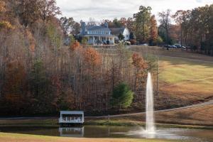 a fountain in a pond in front of a house at Dahlonega Resort and Vineyard in Dahlonega
