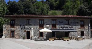 a stone building with an umbrella and tables and chairs at Albergue La Vargona in Camaleño
