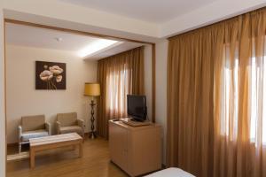 ein Hotelzimmer mit einem TV, einem Sofa und einem Stuhl in der Unterkunft Hotel Casa Sao Nuno in Fátima