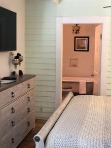 a bedroom with a bed and a dresser at SeaGlass Inn Bed and Breakfast in Melbourne Beach