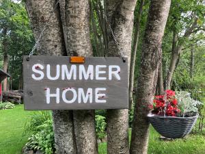 un cartel que lee "Hogar de verano colgando de un árbol" en Summerhome, en Skulte