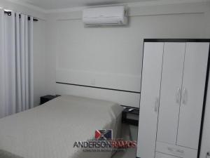 1 dormitorio con 1 cama blanca y armario blanco en 1016 - Locação de Temporada em Bombinhas - Residencial Alameda Verde Apto 103, en Bombinhas